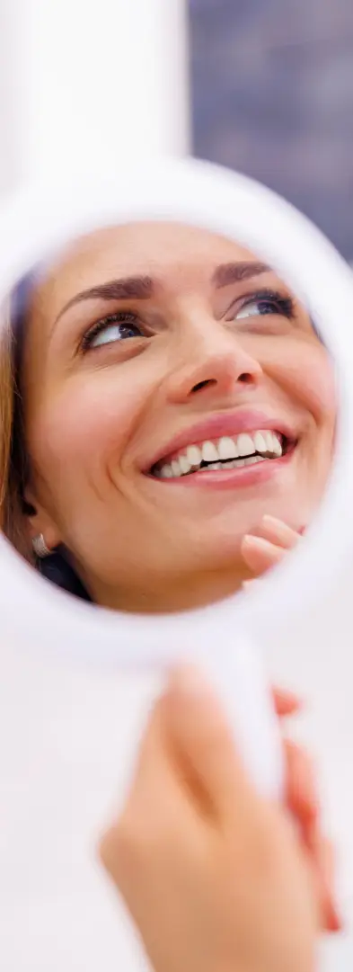 Patient checking smile in mirror at Saratoga Smiles